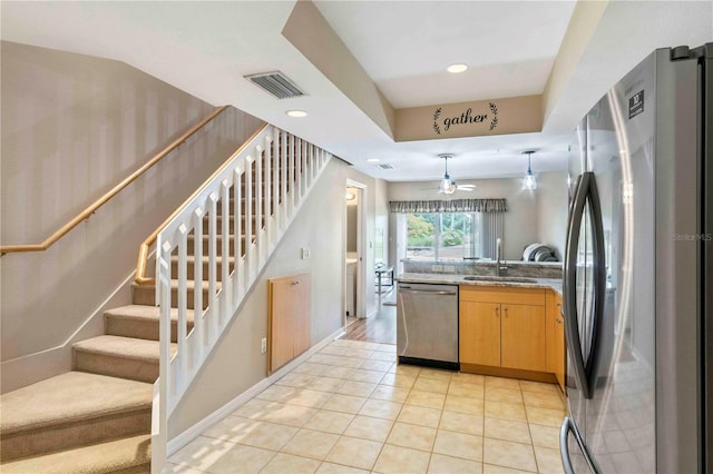 kitchen featuring sink, light tile patterned floors, ceiling fan, appliances with stainless steel finishes, and light stone counters