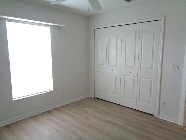 unfurnished bedroom with a closet, light hardwood / wood-style floors, and ceiling fan