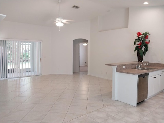 kitchen featuring stainless steel dishwasher, sink, white cabinetry, and light tile patterned flooring