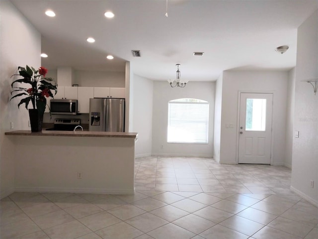 kitchen featuring kitchen peninsula, light tile patterned flooring, a notable chandelier, white cabinetry, and appliances with stainless steel finishes