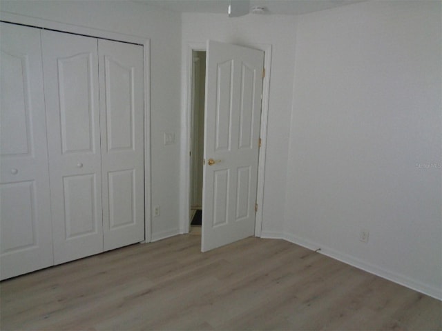 unfurnished bedroom with light hardwood / wood-style flooring and a closet