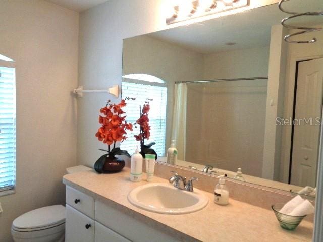 bathroom with vanity, a shower with shower curtain, and toilet