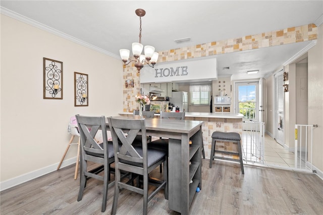 dining space featuring light hardwood / wood-style flooring, a chandelier, and ornamental molding