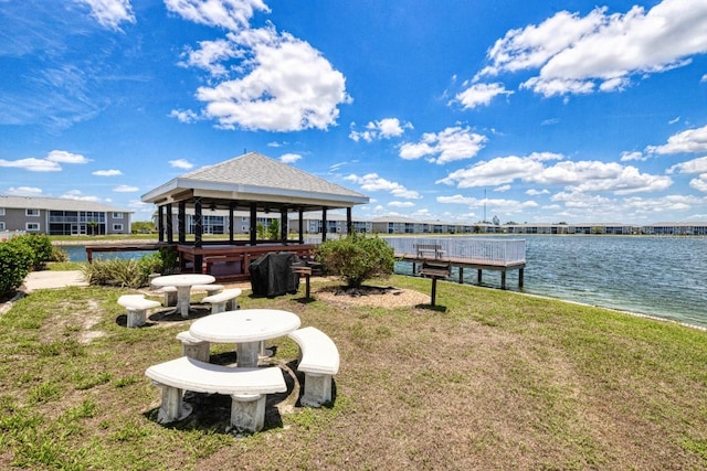 dock area featuring a gazebo, a water view, and a lawn