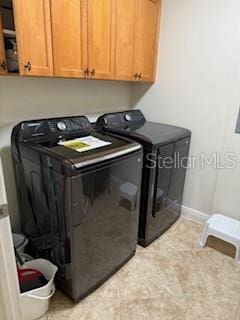 clothes washing area featuring cabinet space, baseboards, and washing machine and clothes dryer