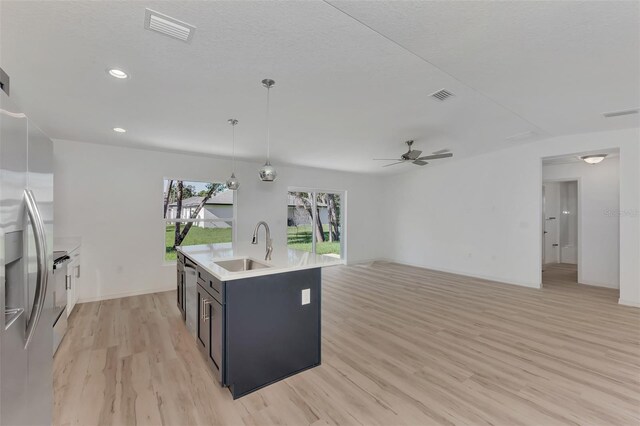 kitchen featuring light hardwood / wood-style flooring, sink, decorative light fixtures, a kitchen island with sink, and ceiling fan