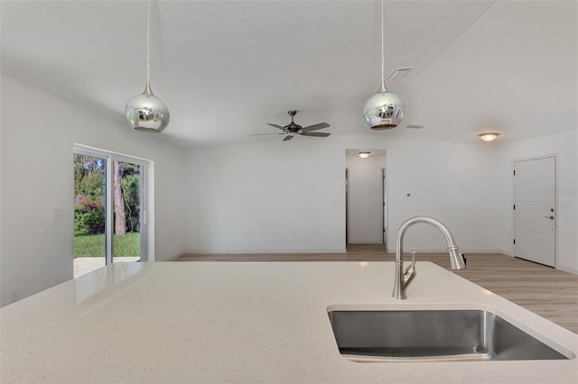 kitchen with light wood-type flooring, decorative light fixtures, sink, and ceiling fan