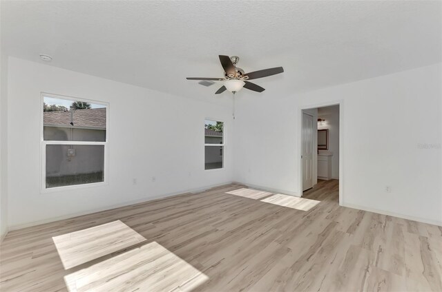 unfurnished room featuring a healthy amount of sunlight, ceiling fan, and light wood-type flooring