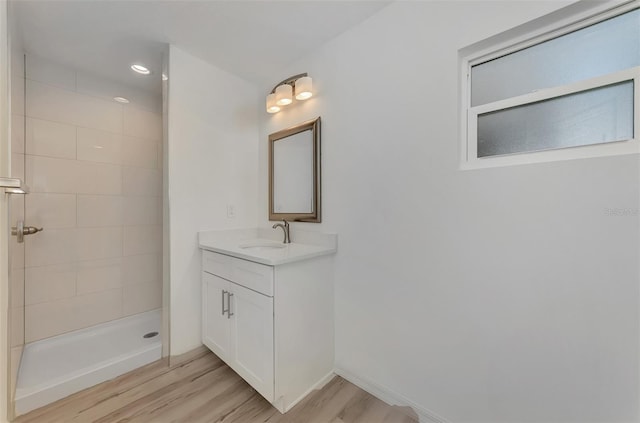 bathroom featuring wood-type flooring, vanity, and a tile shower