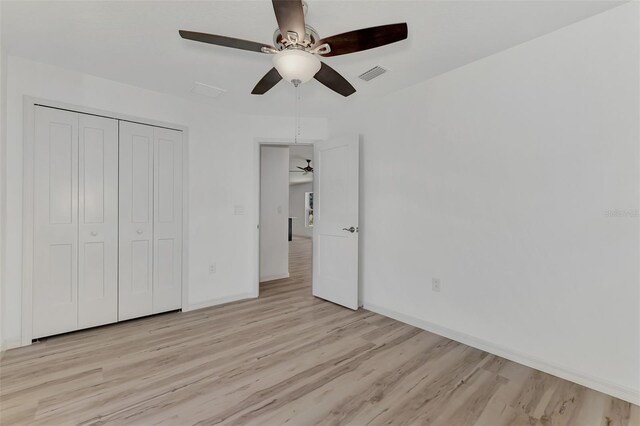 unfurnished bedroom with light hardwood / wood-style floors, a closet, and ceiling fan