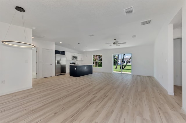 unfurnished living room featuring light wood-type flooring, a textured ceiling, and ceiling fan