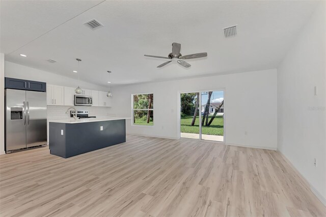 kitchen featuring appliances with stainless steel finishes, hanging light fixtures, backsplash, light wood-type flooring, and ceiling fan