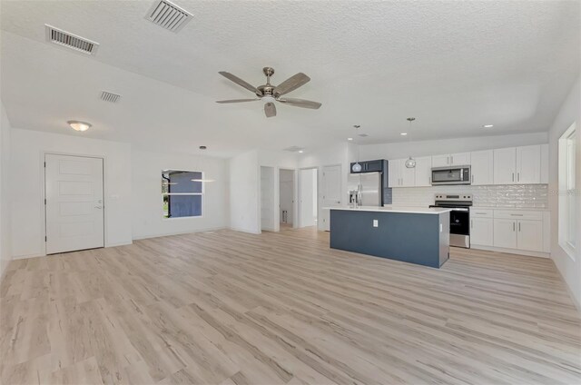 kitchen with white cabinetry, light hardwood / wood-style flooring, a kitchen island, ceiling fan, and stainless steel appliances