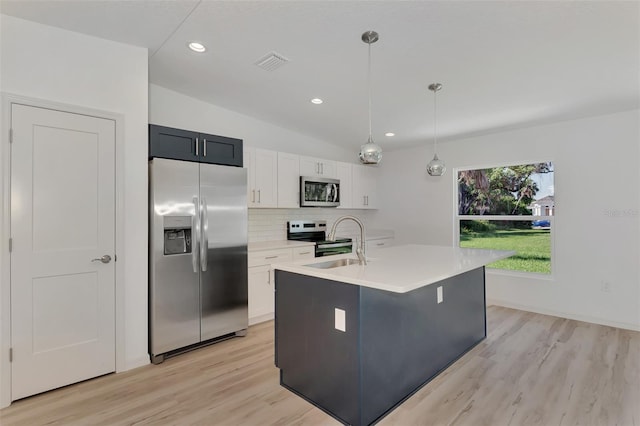 kitchen featuring stainless steel appliances, decorative light fixtures, backsplash, white cabinetry, and a kitchen island with sink