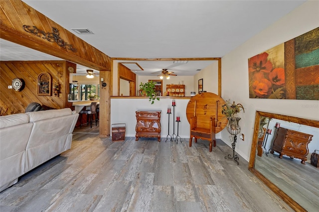 living room with hardwood / wood-style floors, ceiling fan, and wooden walls