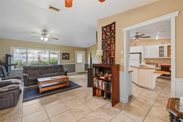 living room with ceiling fan, light tile patterned floors, and vaulted ceiling