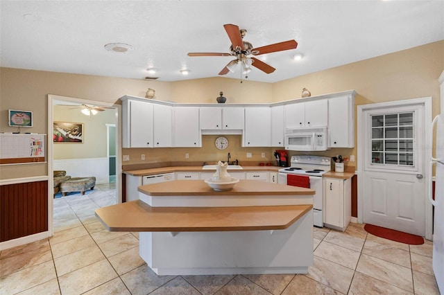 kitchen featuring white cabinetry, a center island, white appliances, vaulted ceiling, and sink