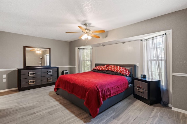 bedroom with a textured ceiling, ceiling fan, and light hardwood / wood-style flooring