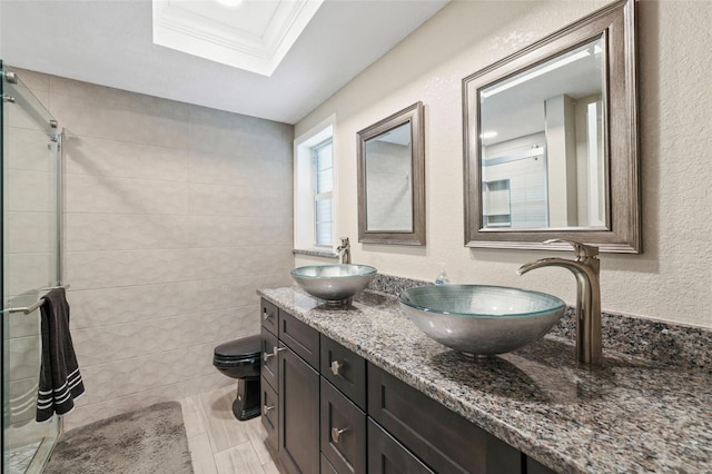 bathroom featuring vanity, a skylight, tile walls, toilet, and crown molding