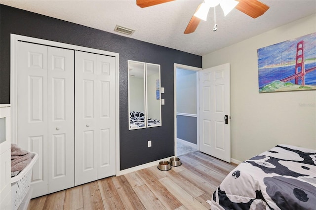 bedroom featuring ceiling fan, light wood-type flooring, and a textured ceiling