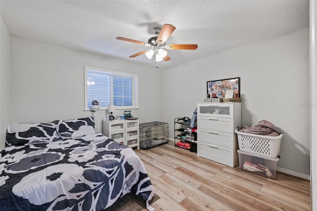 bedroom with ceiling fan, light hardwood / wood-style floors, and a textured ceiling