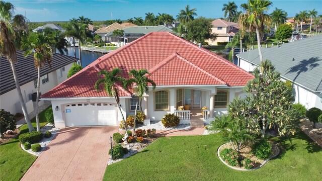 mediterranean / spanish house featuring a garage, a water view, covered porch, and a front yard