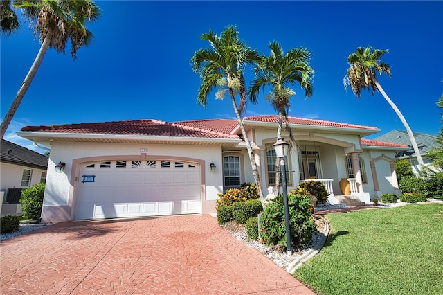 mediterranean / spanish-style home featuring covered porch, a garage, and a front yard