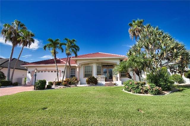 mediterranean / spanish-style home with a front yard, a garage, covered porch, and french doors