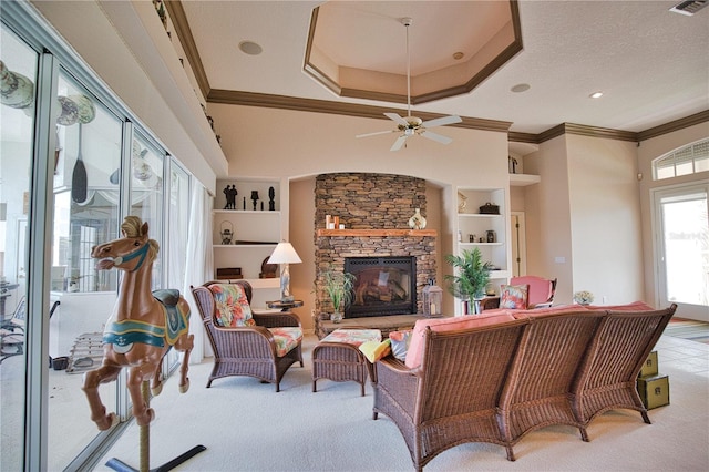 living room featuring ceiling fan, a stone fireplace, built in features, and crown molding