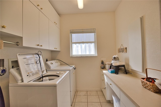 clothes washing area with cabinets, light tile patterned floors, and independent washer and dryer