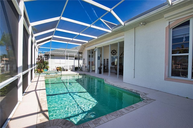 view of pool featuring glass enclosure, a patio, and an in ground hot tub