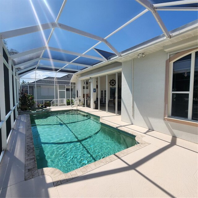 view of swimming pool featuring a patio and glass enclosure