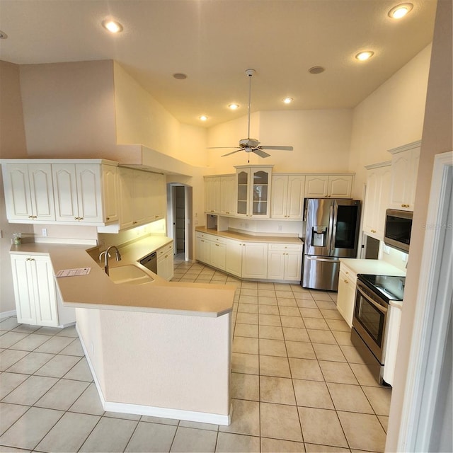 kitchen featuring light tile patterned flooring, appliances with stainless steel finishes, high vaulted ceiling, sink, and kitchen peninsula