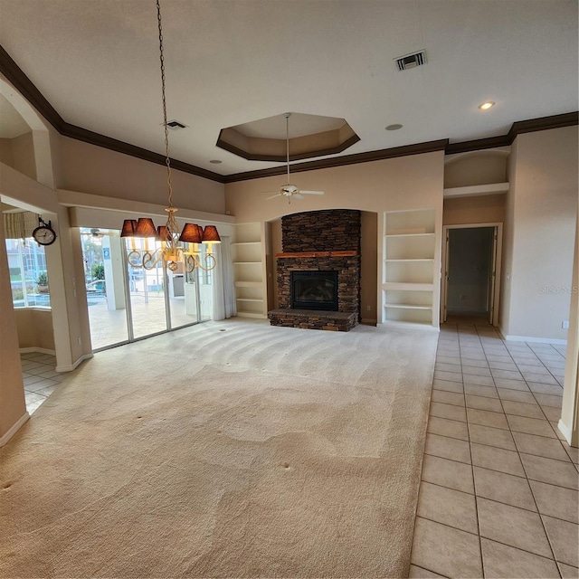 unfurnished living room with built in shelves, ceiling fan, light tile patterned floors, a fireplace, and crown molding