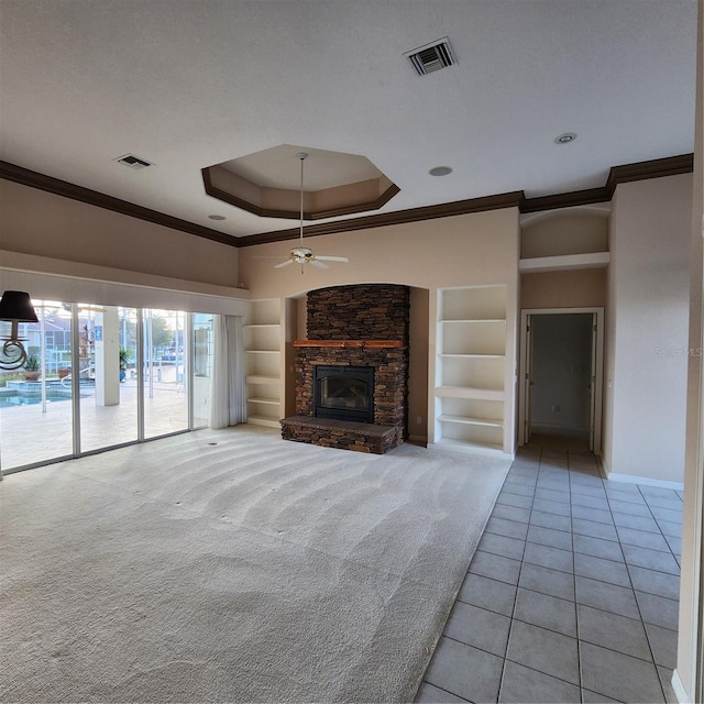 unfurnished living room with built in features, crown molding, ceiling fan, and a fireplace