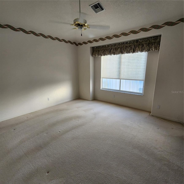 carpeted spare room featuring a textured ceiling and ceiling fan