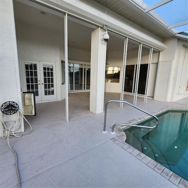 view of swimming pool with french doors, glass enclosure, and a patio area