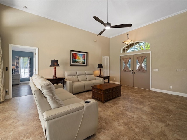 living room with ceiling fan, ornamental molding, and a high ceiling