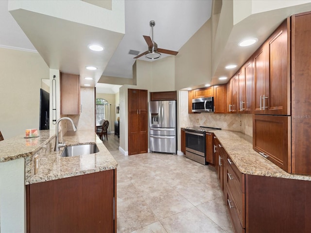 kitchen featuring appliances with stainless steel finishes, sink, decorative backsplash, kitchen peninsula, and light stone countertops