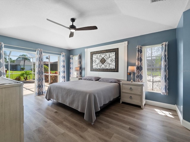 bedroom featuring multiple windows, lofted ceiling, dark hardwood / wood-style flooring, access to outside, and ceiling fan