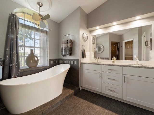 bathroom featuring lofted ceiling, tile walls, vanity, and a tub