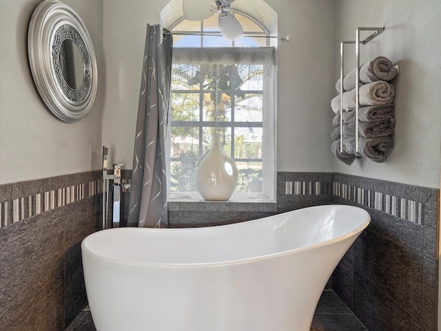 bathroom with tile patterned flooring, a bath, and tile walls