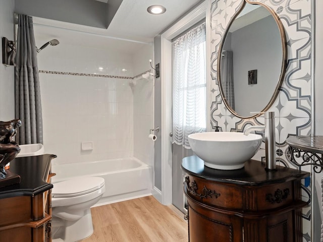 full bathroom with tiled shower / bath, wood-type flooring, toilet, and vanity