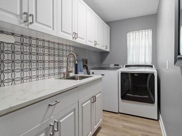 washroom with cabinets, sink, independent washer and dryer, and light wood-type flooring