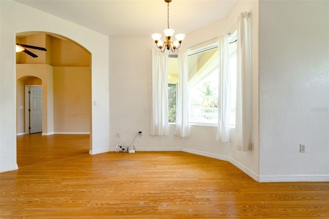 spare room with ceiling fan with notable chandelier and light hardwood / wood-style floors