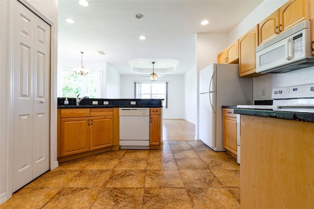 kitchen featuring decorative light fixtures, dark stone countertops, ceiling fan, a raised ceiling, and white appliances