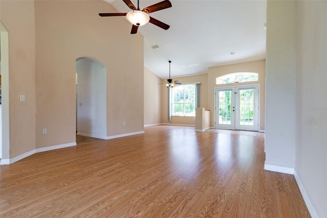 unfurnished living room featuring french doors, ceiling fan, high vaulted ceiling, and light wood-type flooring