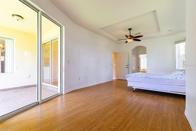 unfurnished bedroom featuring wood-type flooring, access to exterior, and ceiling fan