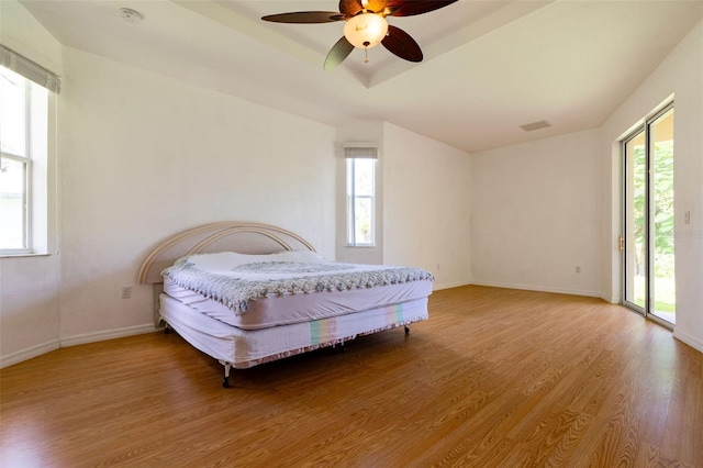 bedroom with hardwood / wood-style flooring, access to outside, ceiling fan, and multiple windows