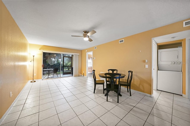 tiled dining area featuring stacked washer and dryer and ceiling fan